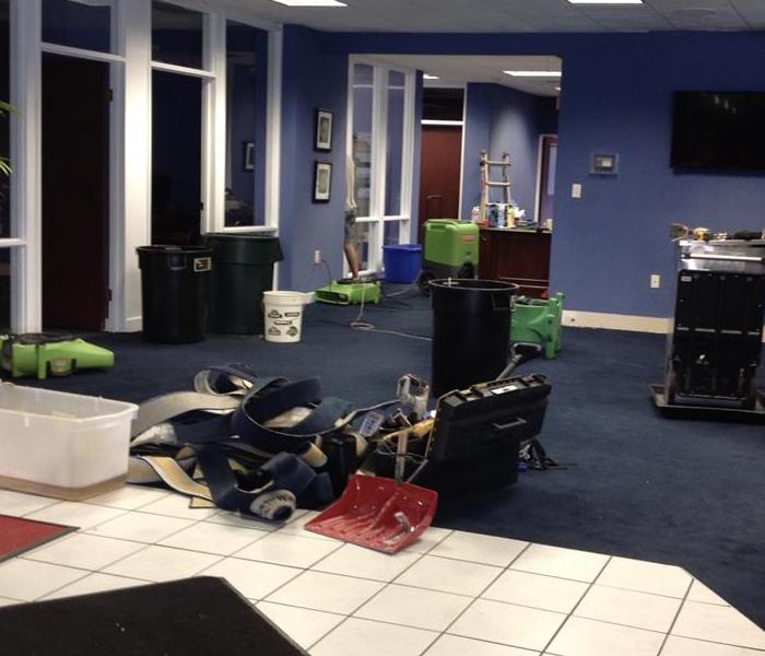 Blue walls, blue carpet, white square tile, 6 air movers, tv on wall, 3 large trashcans, wet carpet in pile on floor
