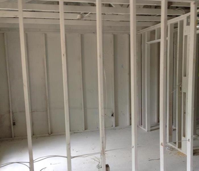 Image of exposed frame work inside a room. Ceiling to floor coverage of white primer.